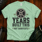 Fitness T-Shirt — “Years Built This, Not Shortcuts” Weightlifting Plate Tee