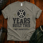 Fitness T-Shirt — “Years Built This, Not Shortcuts” Weightlifting Plate Tee